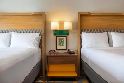 a hotel room with two beds and a night stand at Holiday Inn Toledo - Maumee I-80/90 by IHG in Maumee