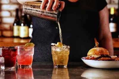 a person is making cocktails at a bar at Holiday Inn Toledo - Maumee I-80/90 by IHG in Maumee