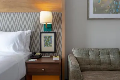 a bed and a chair in a hotel room at Holiday Inn Toledo - Maumee I-80/90 by IHG in Maumee