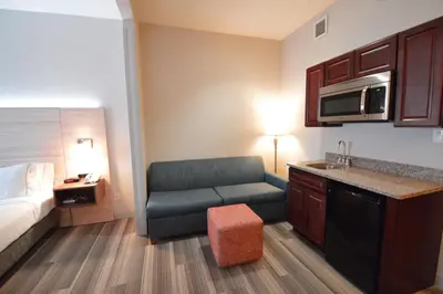 a hotel room with a bed and a couch and a kitchen at Holiday Inn Express Toledo-Oregon by IHG in Oregon