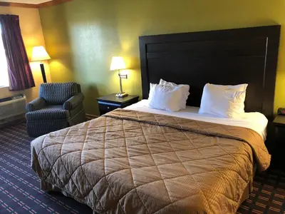 a hotel room with a bed and a chair at Americas Best Value Inn Maumee/Toledo in Maumee