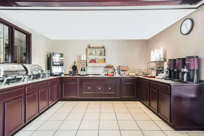 a large kitchen with brown cabinets and a clock on the wall at Hawthorn Extended Stay by Wyndham Dayton in Dayton