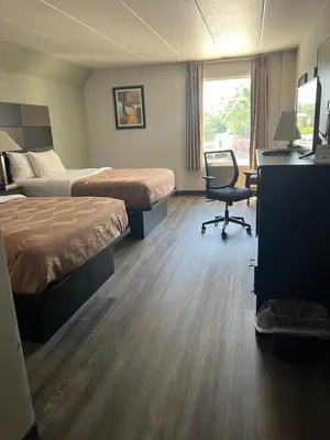 a hotel room with two beds and a desk and a chair at Quality Inn & Suites in Cincinnati