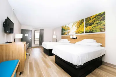 a hotel room with two beds and a flat screen tv at Days Inn by Wyndham Cincinnati East in Cherry Grove