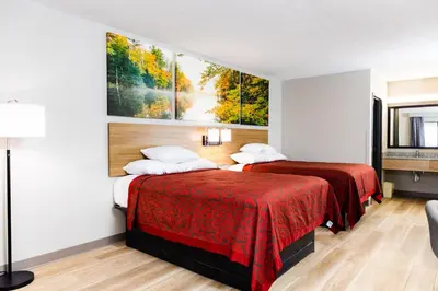 two beds in a hotel room with paintings on the wall at Days Inn by Wyndham Cincinnati East in Cherry Grove