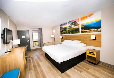 a hotel room with a bed and a flat screen tv at Days Inn by Wyndham Cincinnati East in Cherry Grove