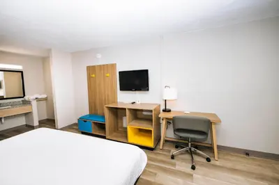 a hotel room with a bed and a desk and a television at Days Inn by Wyndham Cincinnati East in Cherry Grove