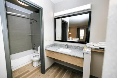 a bathroom with a sink and a toilet and a mirror at Days Inn by Wyndham Cincinnati East in Cherry Grove