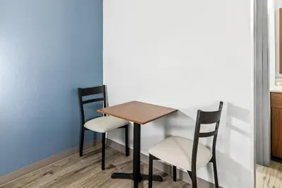 a table and two chairs next to a wall at HomeTowne Studios by Red Roof Florence, KY-Cincinnati Airport in Florence
