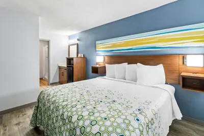 a hotel room with a bed with a colorful bedspread at HomeTowne Studios by Red Roof Florence, KY-Cincinnati Airport in Florence
