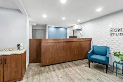 an office with a reception desk and a blue chair at HomeTowne Studios by Red Roof Florence, KY-Cincinnati Airport in Florence