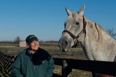 a man standing next to a horse behind a fence at Baymont by Wyndham Georgetown Lexington North in Georgetown