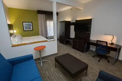 a hotel room with a blue couch and a desk at Holiday Inn Express Wilmington by IHG in Wilmington