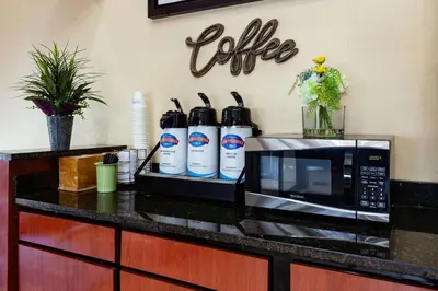 a kitchen counter with a microwave and bottles of coffee at Baymont by Wyndham Perrysburg-Toledo in Perrysburg