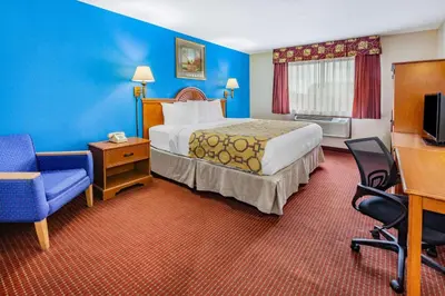 a hotel room with a bed and a chair at Baymont by Wyndham Perrysburg-Toledo in Perrysburg