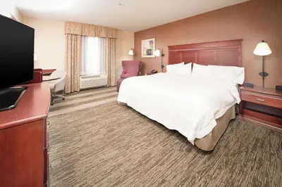 a hotel room with a bed and a flat screen tv at Hampton Inn & Suites Greensburg in Greensburg