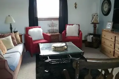 a living room with red chairs and a coffee table at Picasso's Condo in Van Wert