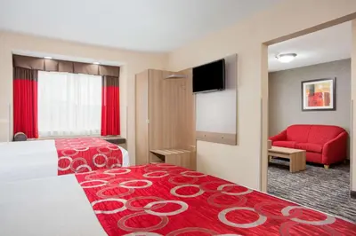 a hotel room with a bed and a red couch at Microtel Inn & Suites by Wyndham Charleston in Charleston