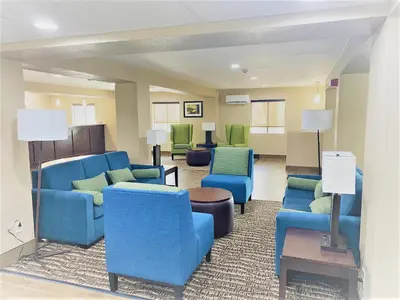 a living room with blue furniture and green chairs at Comfort Inn Charleston South in Charleston