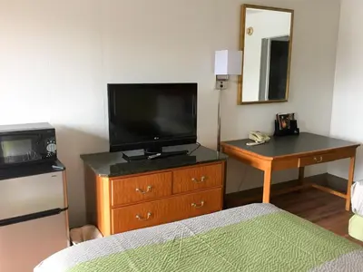 a bedroom with a television and a dresser with a bed at Motel 6-Parkersburg, WV in Parkersburg