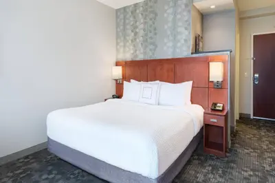 a bedroom with a large white bed and a mirror at Courtyard by Marriott Pittsburgh Washington Meadow Lands in Washington