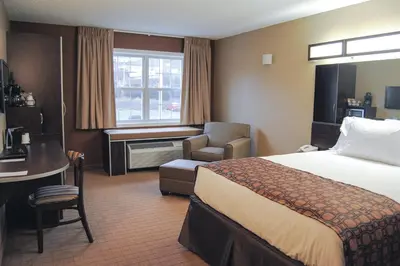 a hotel room with a bed and a chair and a window at Microtel Inn & Suites By Wyndham Mineral Wells/Parkersburg in Mineralwells