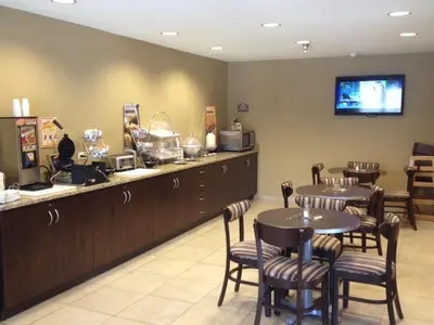 a restaurant with a counter and tables and chairs at Microtel Inn & Suites By Wyndham Mineral Wells/Parkersburg in Mineralwells