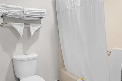 a bathroom with a toilet and a shower with towels at Days Inn by Wyndham Huntington in Pea Ridge