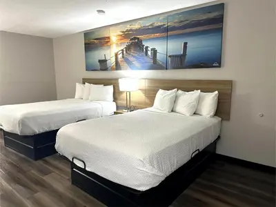 a hotel room with two beds and a painting on the wall at Days Inn by Wyndham Huntington in Pea Ridge