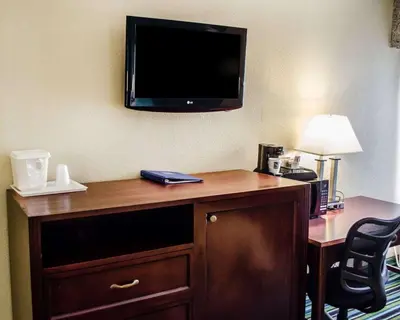 a hotel room with a desk with a television on the wall at Quality Inn & Suites Medina - Akron West in Medina