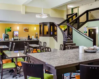 a dining room with tables and chairs and a staircase at Quality Inn & Suites Medina - Akron West in Medina