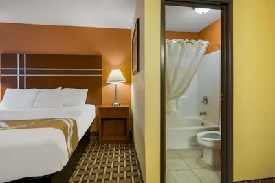a hotel room with a bed and a bathroom with a toilet at Quality Inn Ashland East in Ashland