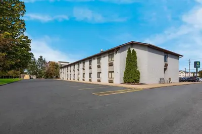 a large white building with a tree in a parking lot at Quality Inn Ashland East in Ashland