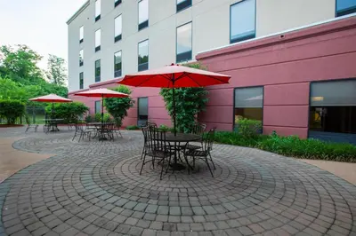 a patio with tables and chairs with umbrellas in front of a building at Hampton Inn & Suites Wilder in Wilder