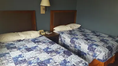 a hotel room with two beds and a clock between them at Travel Inn in Sharonville