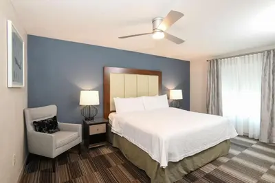 a bedroom with a white bed and a chair at Homewood Suites Cincinnati Airport South-Florence in Florence