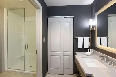 a bathroom with a shower and two sinks and a mirror at Homewood Suites Cincinnati Airport South-Florence in Florence