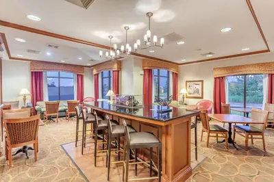 a living room with a bar with chairs and tables at Hampton Inn Auburn in Auburn