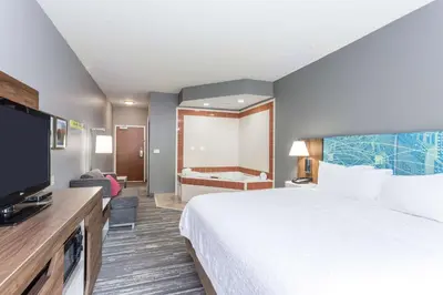a hotel room with a bed and a tub at Hampton Inn Auburn in Auburn