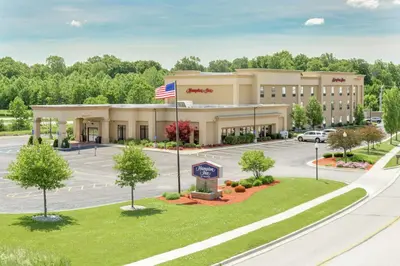 an office building with an american flag in a parking lot at Hampton Inn Auburn in Auburn