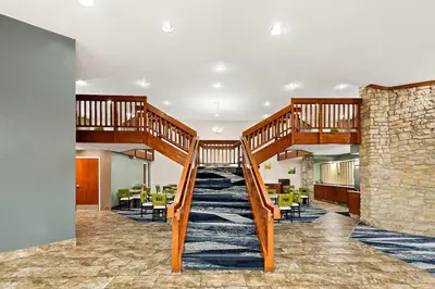 a lobby with a staircase with chairs and tables at Quality Inn Mason Near Kings Island in Mason