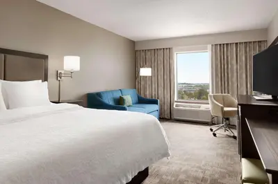 a hotel room with a bed and a blue chair at Hampton Inn Stow in Stow