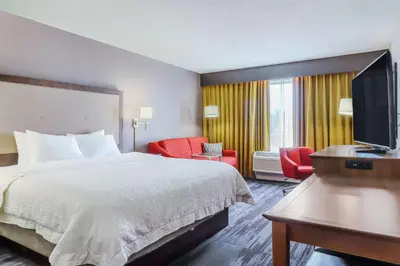 a hotel room with a bed and a flat screen tv at Hampton Inn Heath in Heath