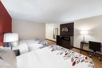 a hotel room with two beds and a desk at Red Roof Inn Fort Wayne in Fort Wayne
