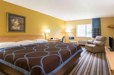 a hotel room with a bed and a chair at Super 8 by Wyndham Medina in Medina