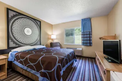 a hotel room with a bed and a flat screen tv at Super 8 by Wyndham Medina in Medina