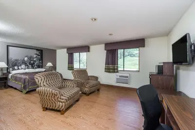 a bedroom with a bed and two chairs and a television at Super 8 by Wyndham Zanesville in Zanesville