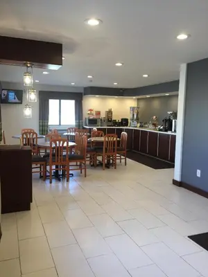 a dining room with tables and chairs and a kitchen at Super 8 by Wyndham Zanesville in Zanesville