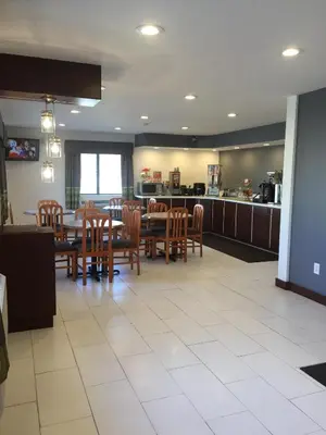 a dining room with tables and chairs and a kitchen at Super 8 by Wyndham Zanesville in Zanesville