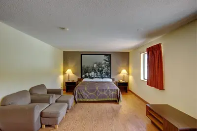 a hotel room with a bed and a couch at Super 8 by Wyndham Zanesville in Zanesville